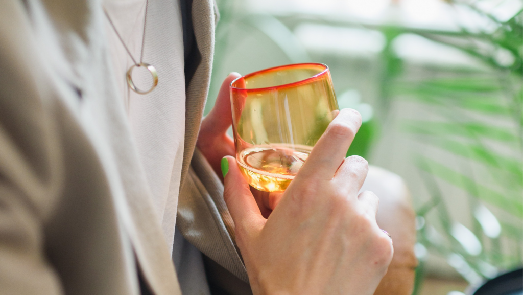 Cropped close up of a female holding an orange glass