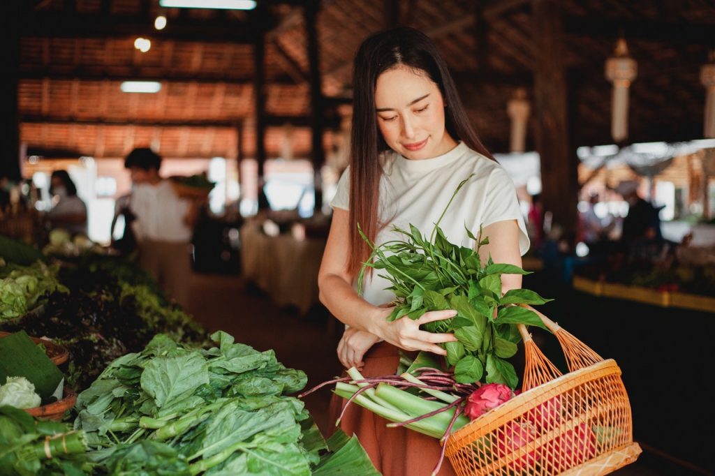 Young girl loading her straw basket with produce from a market