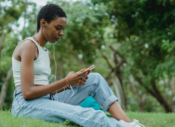 Woman sitting on a grassy hill looking down at her smartphone